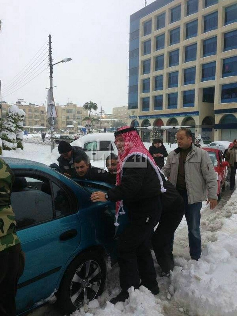 بالصور..الملك يدفع سيارات عالقة بشارع الجاردنز ويساعد المواطنين Image