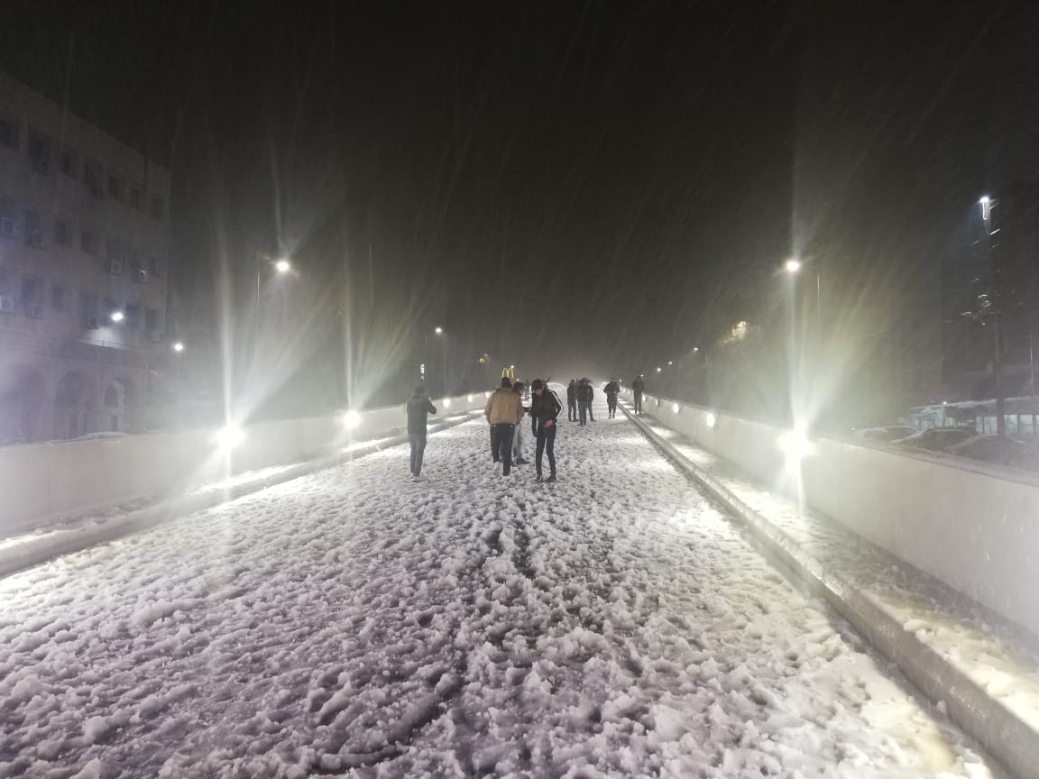 بالصور  .. "الباص السريع" ساحة للعب في الثلج بعمان