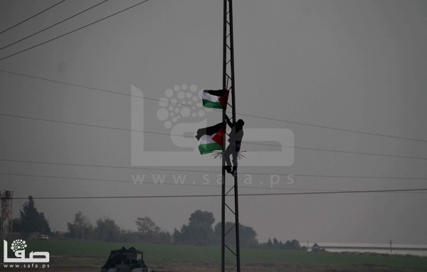 بالصور : رفع علم فلسطين على السياج الأمني رغم الرصاص